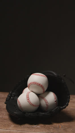 Vídeo-Vertical-De-Cerca-Estudio-De-Béisbol-Bodegón-Con-Pelotas-Y-Guante-De-Receptor-En-El-Suelo-De-Madera-1